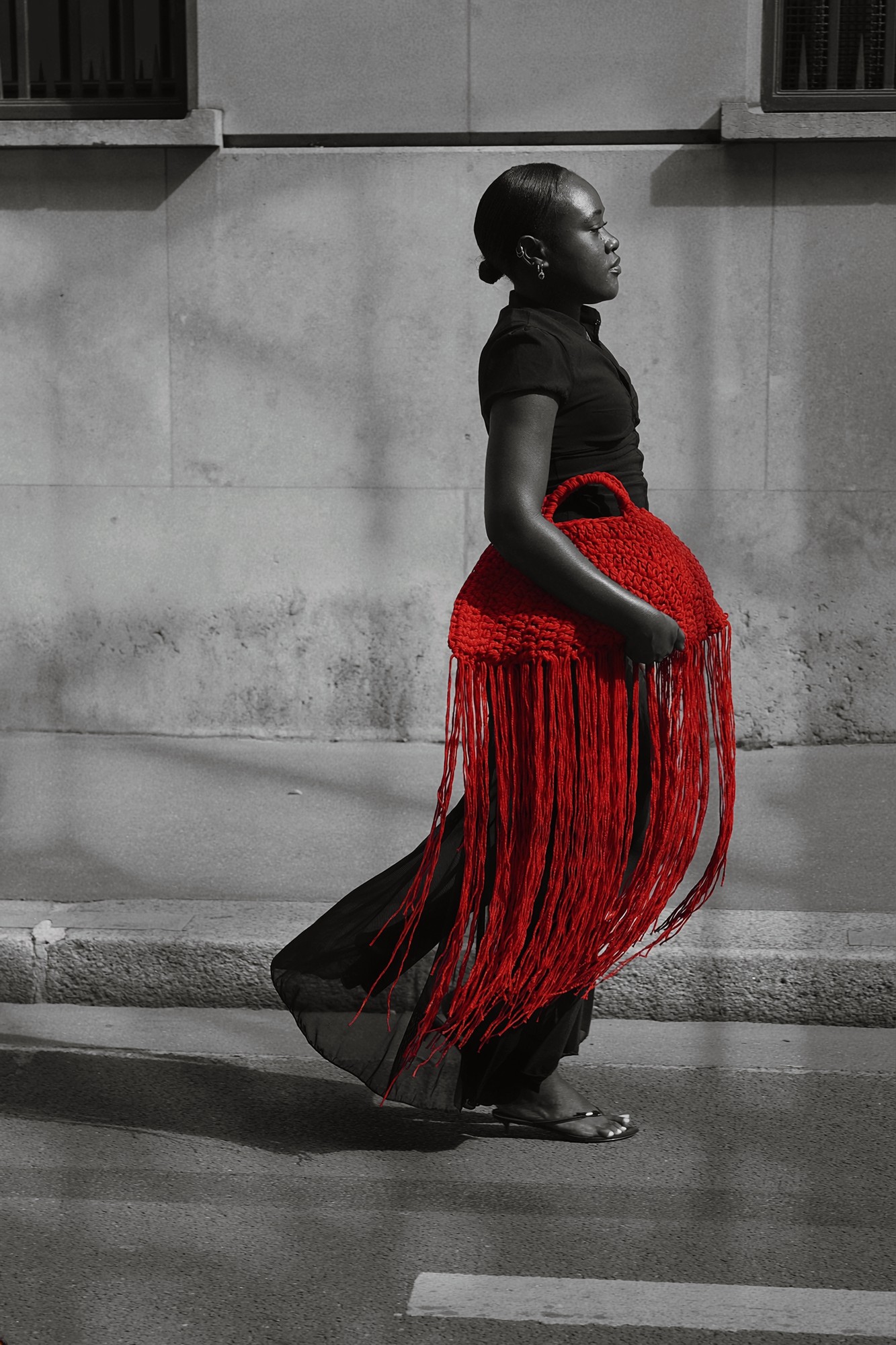 Femme marchant dans la rue avec un sac rouge à franges, photo noir et blanc